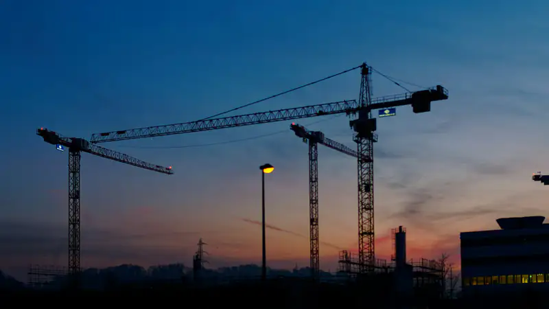 Tower cranes over a construction site at dusk